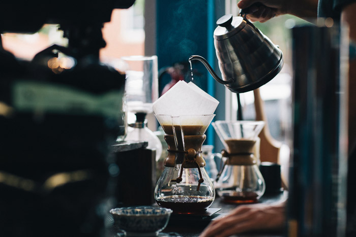 A barista pouring coffee into a v60 filter at a busy cafe 