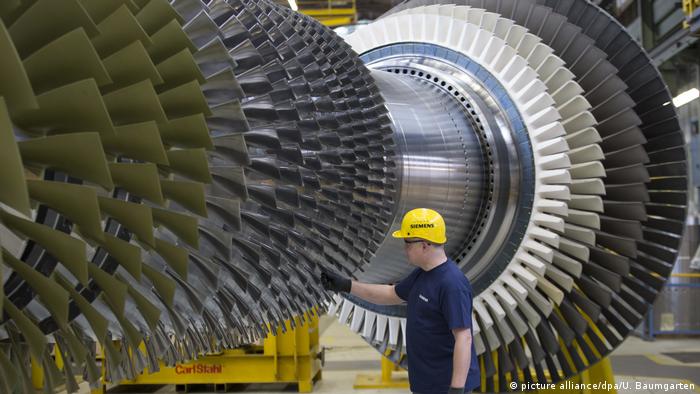 Рабочий на заводе в Берлине перед газовой турбиной Siemens 